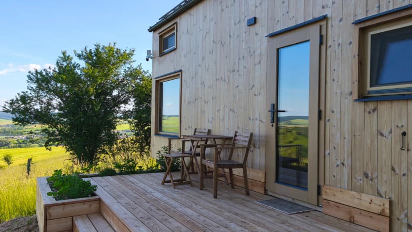 Terasa tiny house Glamping Meze u Bučovic se stolem a výhledem do krajiny
