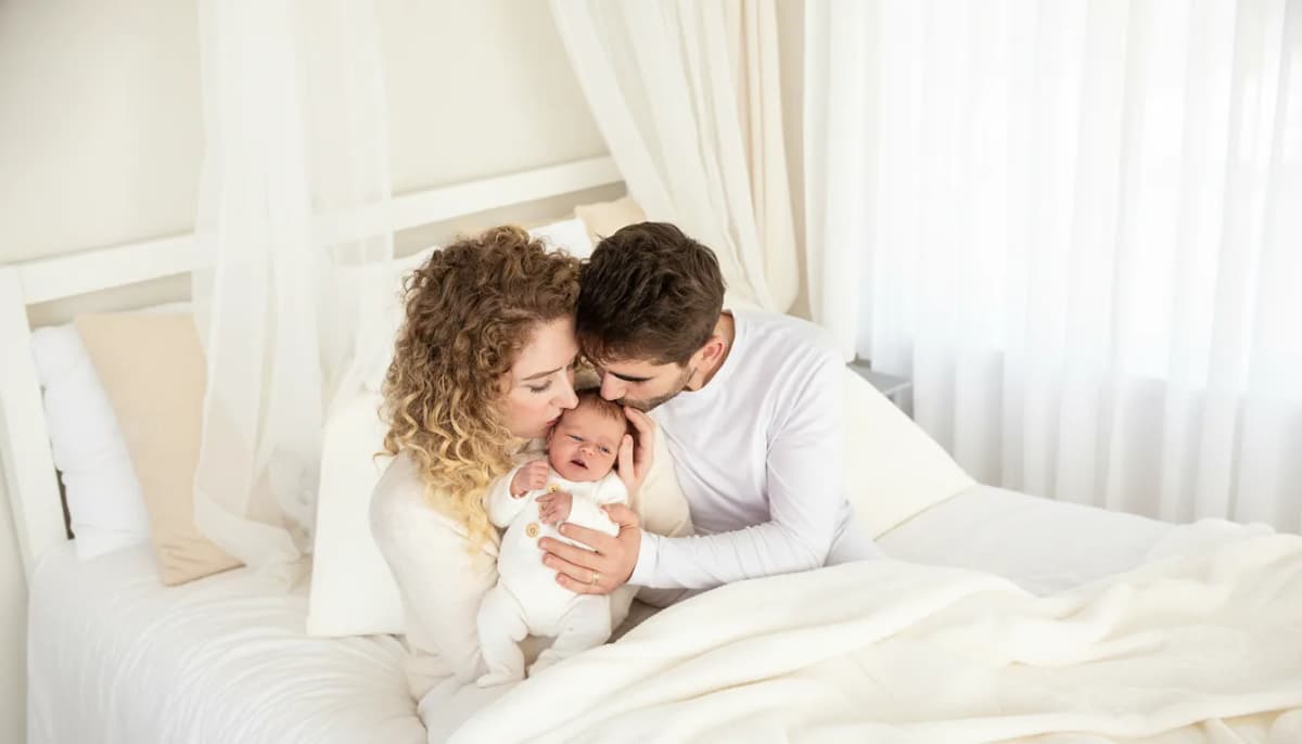 Newborn focení Brno, rodiče s miminkem na bílé posteli ve skandinávském ateliéru, fotografka Marcela Kramářová, Čechyně nedaleko Brna