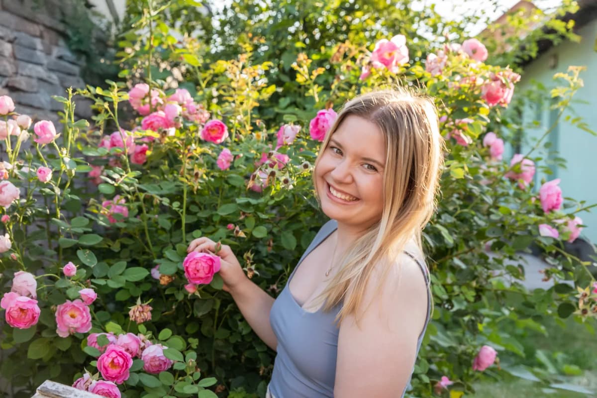 Mladá žena u kvetoucího keře růžových růží, letní focení na zahradě u Brna