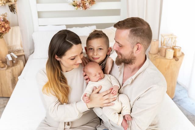 Newborn focení Brno s bratříčkem, rodiče se dvěma syny v ateliéru v Čechyni nedaleko Brna, starší bratr objímá novorozeně, neutrální béžové tóny